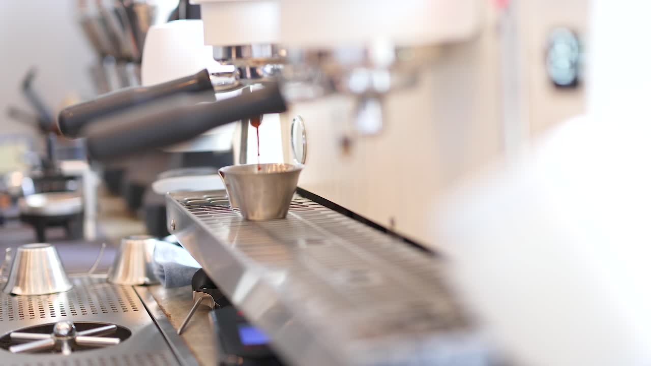 A coffee machine in a Phuket cafe brews espresso. Warm lighting and close-up angles highlight the brewing process