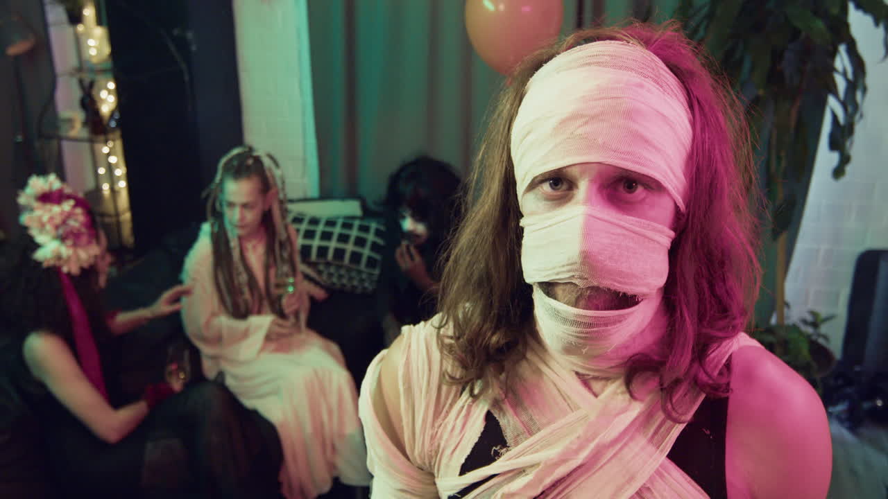 мужчина смотрит на камеру на вечеринке на хэллоуин.