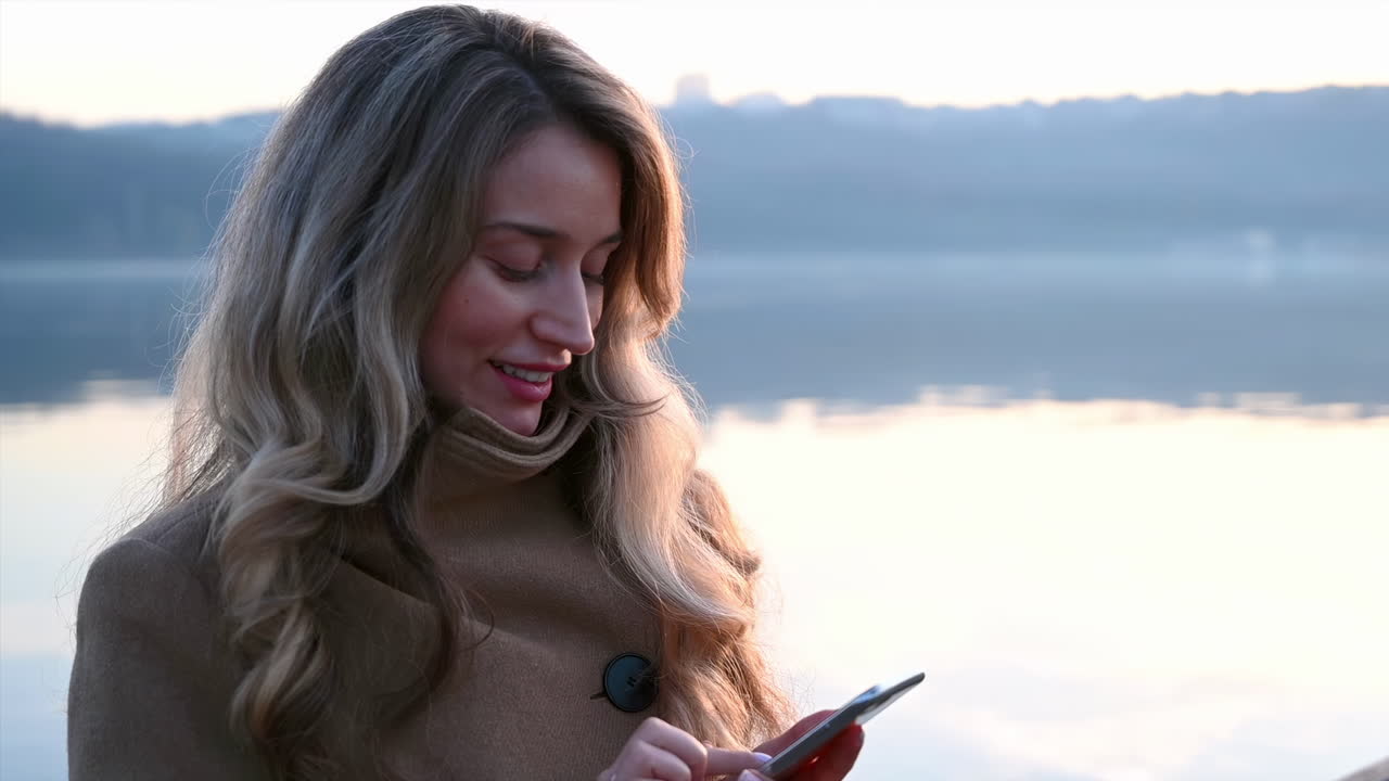 Smiling young woman typing in her phone in park