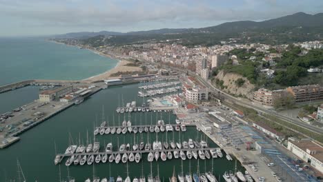 Puerto-Deportivo-De-Arenys-De-Mar-En-El-Maresme-Provincia-De-Barcelona-Pequeñas-Embarcaciones-Amarradas-Pueblo-Pesquero-Imágenes-Aéreas