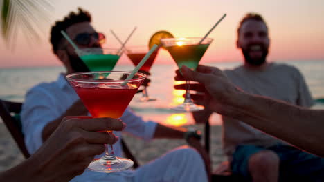 friends celebrating sunset at beach with cocktails