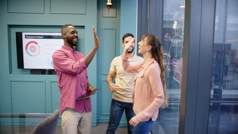 celebrating success, diverse business team high-fiving in modern office setting