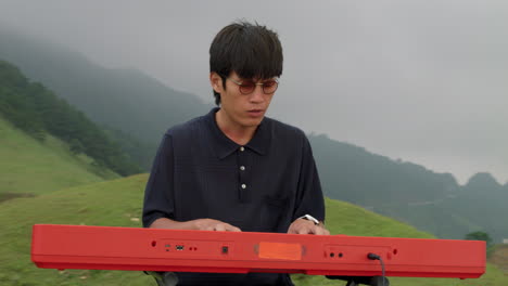 musician playing keyboard outdoors, orbital. mist covered background