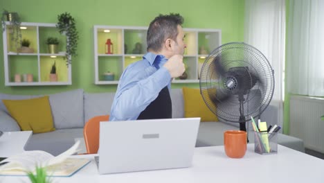 Trabajador-De-Oficina-En-Casa-Que-Está-Abrumado-Por-El-Calor.-Utiliza-Un-Ventilador.