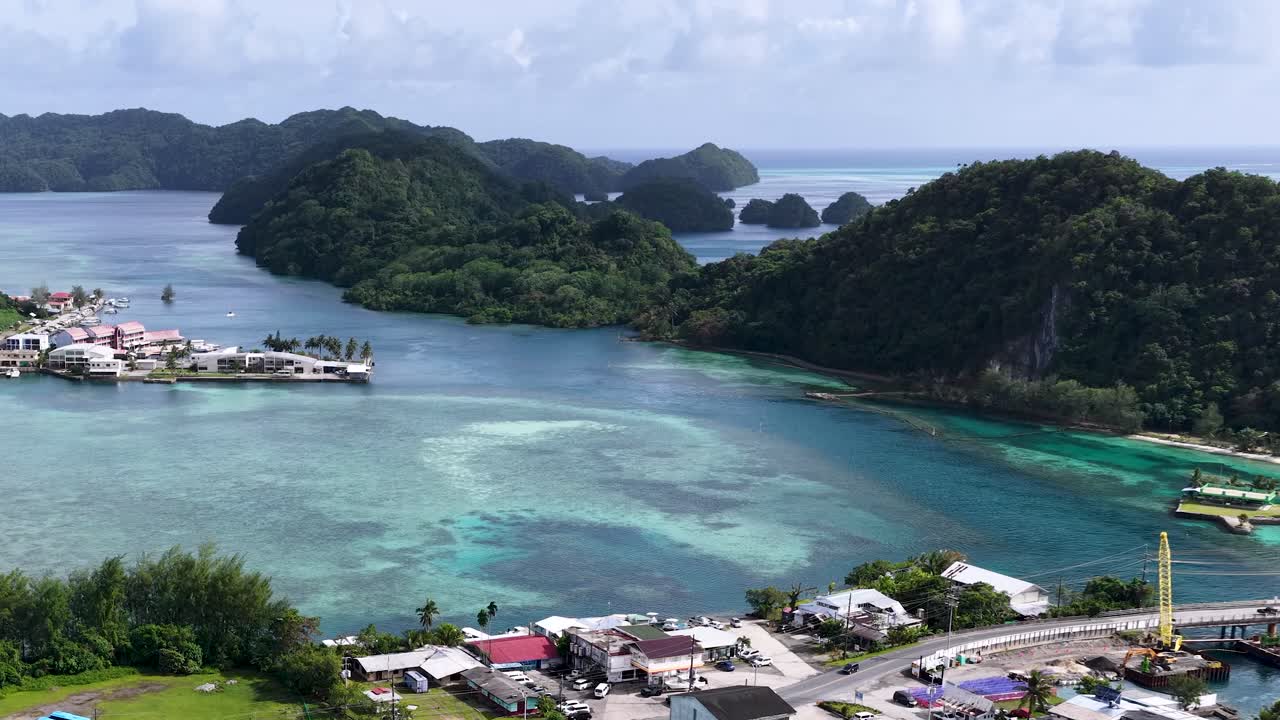 Vista aérea en picada de una ciudad costera tropical y una bahía turquesa en Palaos, Micronesia.