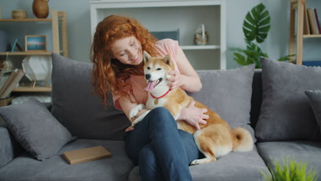 woman cuddling with shiba inu dog on a couch