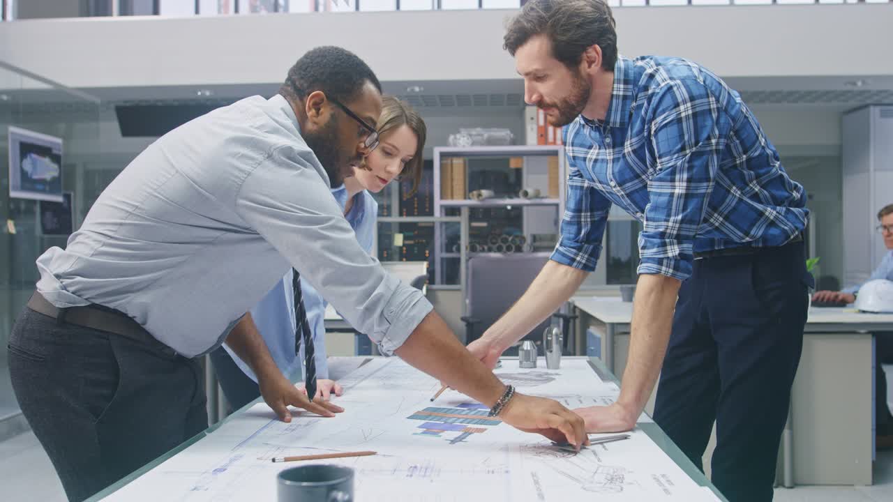 en la instalación de ingeniería industrial: la diseñadora trabaja con el ingeniero industrial y el maestro técnico, tienen discusión, analizan los borradores técnicos de diseño del motor que están sobre la mesa