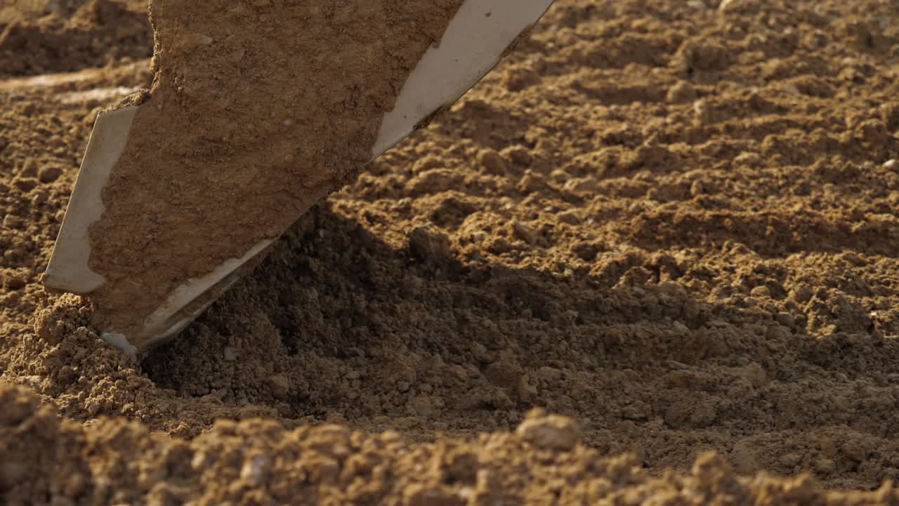 Escavatore giallo che scava il terreno al rallentatore, primo piano