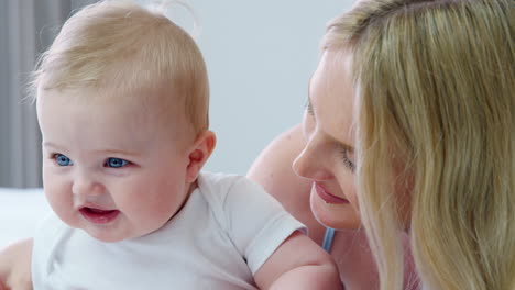 mother lying on bed at home with baby son