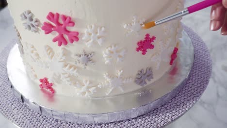 decorating round funfetti cake with pink and white fondant snowflakes.