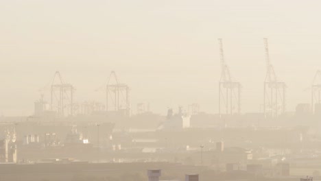 general view of cityscape with multiple buildings and shipyard covered in fog