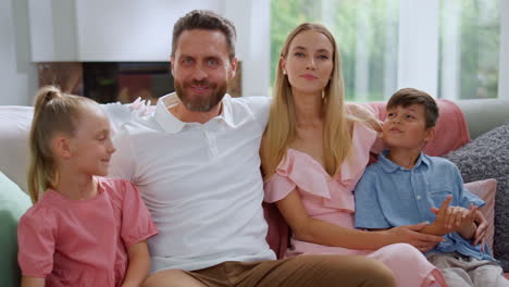 Family-sitting-on-sofa-in-living-room.-Woman-and-man-talking-with-children