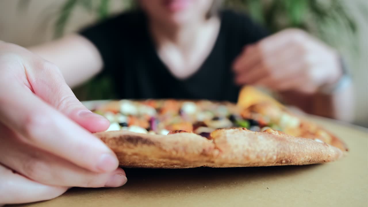 검은 티셔츠를 입은 여자가 집에서 피자를 먹습니다.