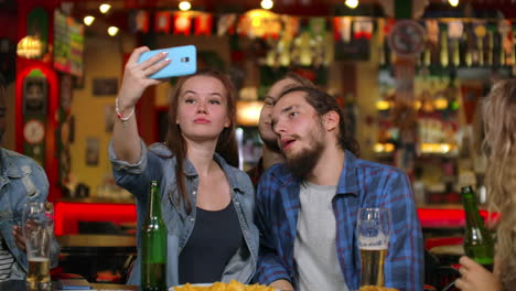 friends take pictures on the phone at the bar make a shared photo on the phone. party with friends at the bar with beer.