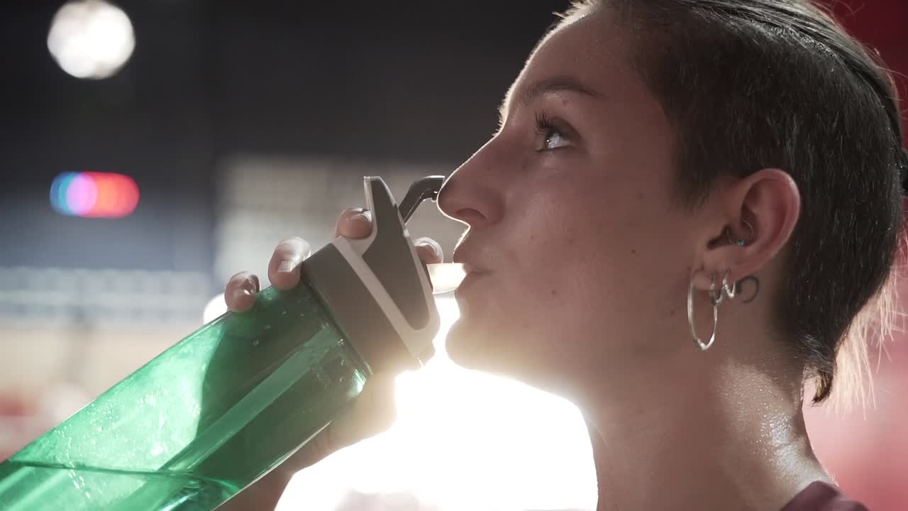 mujer bebiendo agua después del entrenamiento