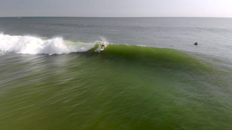 epic drone tracking shot of surfer riding a wave