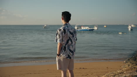 Un-Hombre-Asiático-Ve-El-Mar-En-La-Playa-De-Bali-En-Vacaciones-Gafas-De-Sol-Desde-Atrás