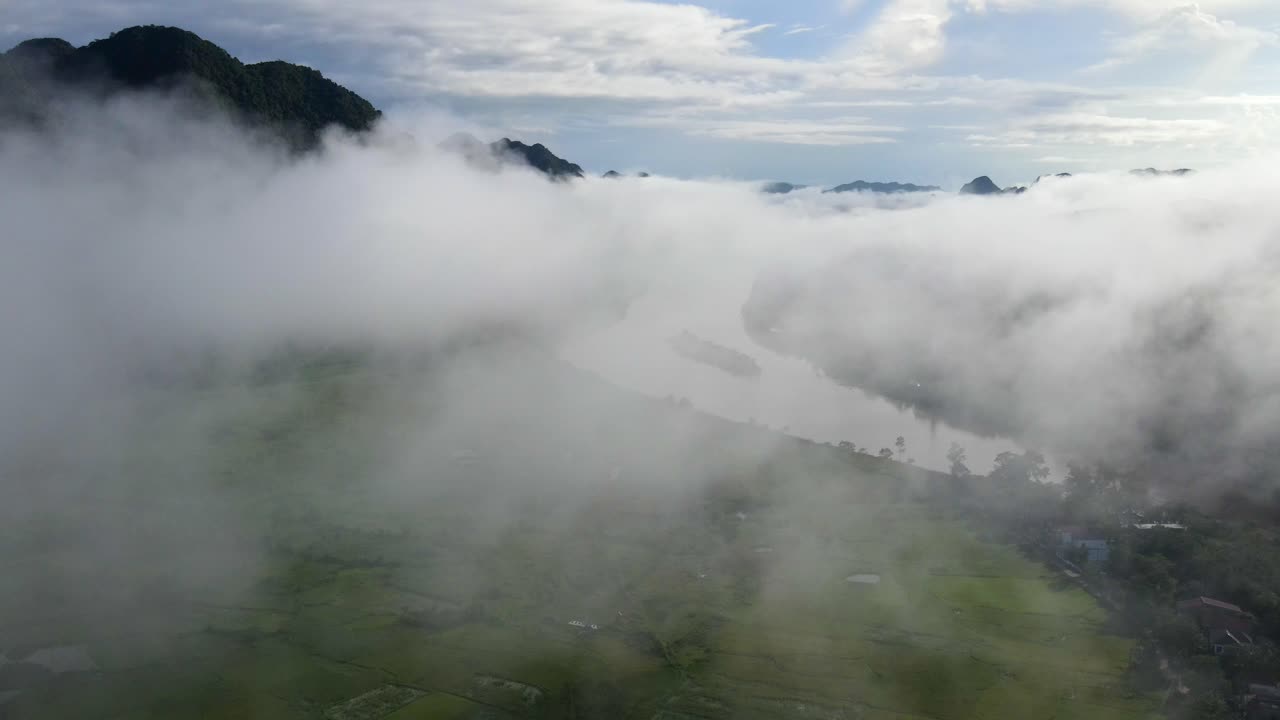Drone panning the thin cloudy mist with rice paddies and windy river lurking behind Phong Nha Viet Nam