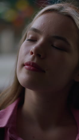 dama de vestido rosado está de pie con los ojos cerrados, mirando relajado y pacífico, su rostro está suavemente iluminado, con una expresión feliz, el fondo es borroso, con estructuras coloridas