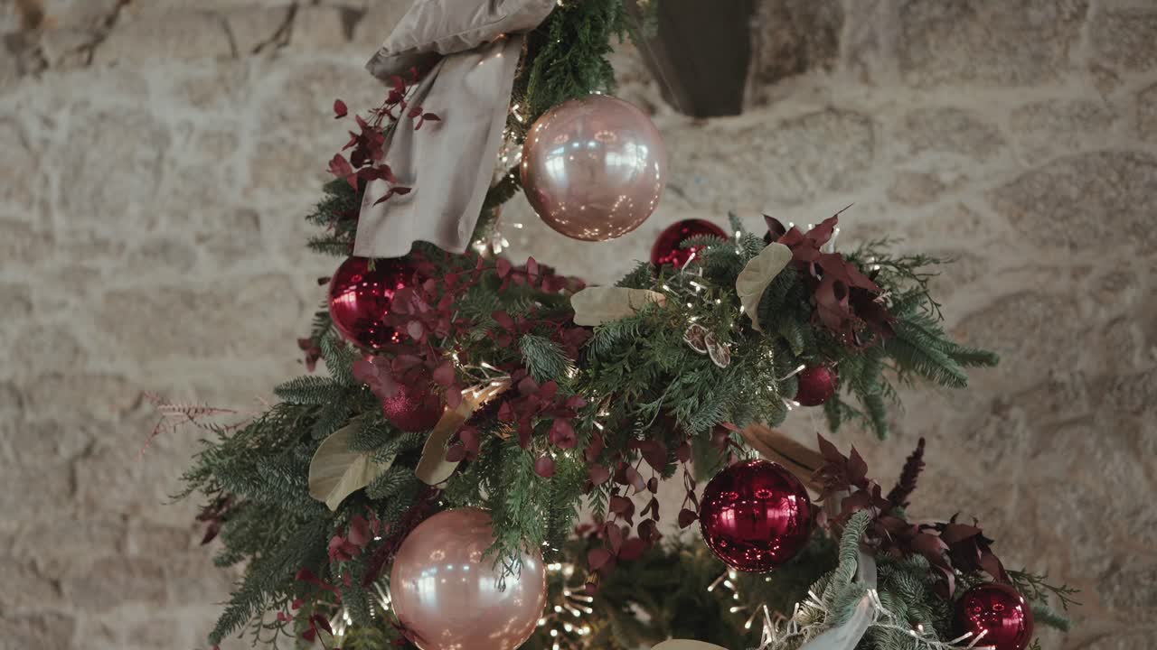 Visão aproximada de uma árvore de Natal decorada com enfeites vermelhos, vegetação e luzes