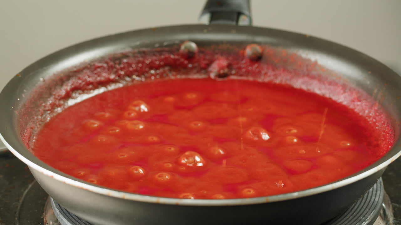 Chicken in tomato sauce is boiling on a frying pan with spices. Cooking tomato sauce curry with chicken fillet. Traditional Italian Mexican Asian dish. High quality studio shot for cafe, restaurant close up.