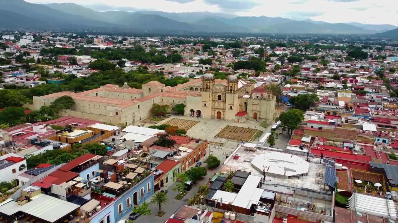 Una vista aerea mozzafiato e cinematografica dall'alto con drone che cattura la storica Chiesa di Santo Domingo de Guzmán e i suoi vasti giardini dell'ex monastero a Oaxaca de Juárez, Messico.