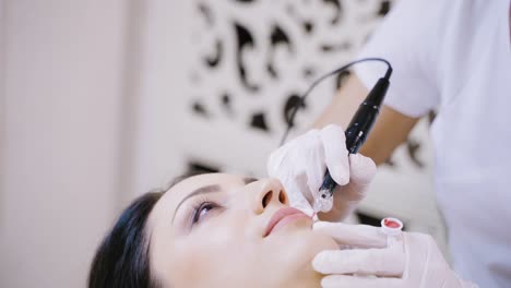 a professional tattoo artist makes lip makeup for the client in the beauty salon. close-up. blurred background.