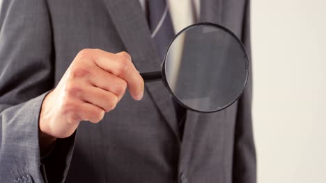 Mid-section-of-businessman-holding-magnifying-glass