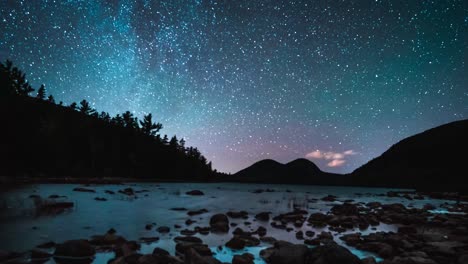 lapso de tiempo de las estrellas de la galaxia de la vía láctea en la noche sobre un lago con árboles y montañas en la distancia
