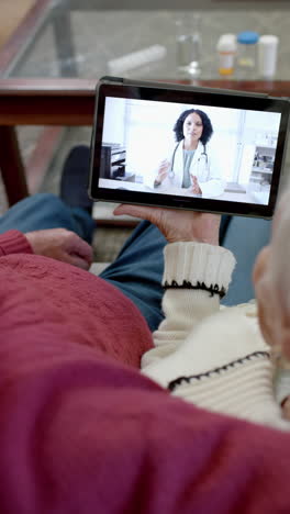 vertical video of senior caucasian couple using tablet for consultation with doctor, slow motion