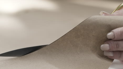 woman cutting brown craft paper with scissors