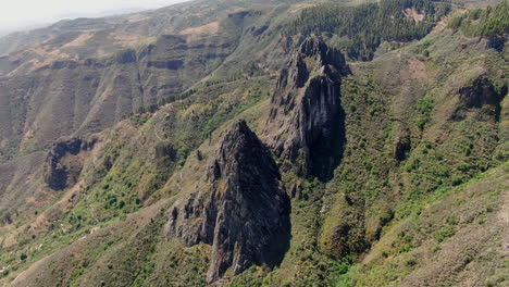 Aerial-view-in-orbit-over-the-fantastic-rock-formations-of-Roque-Chico-and-Roque-Grande-in-the-nature-reserve,-on-the-island-of-Gran-Canaria-on-a-sunny-day