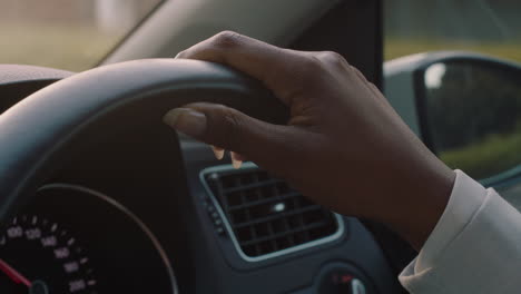 woman driving car with hands on steering wheel to control vehicle in city travelling on the road at rush hour to destination