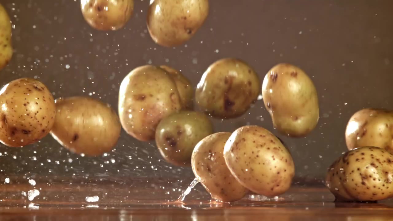 Patate fresche che cadono e schizzano acqua al rallentatore