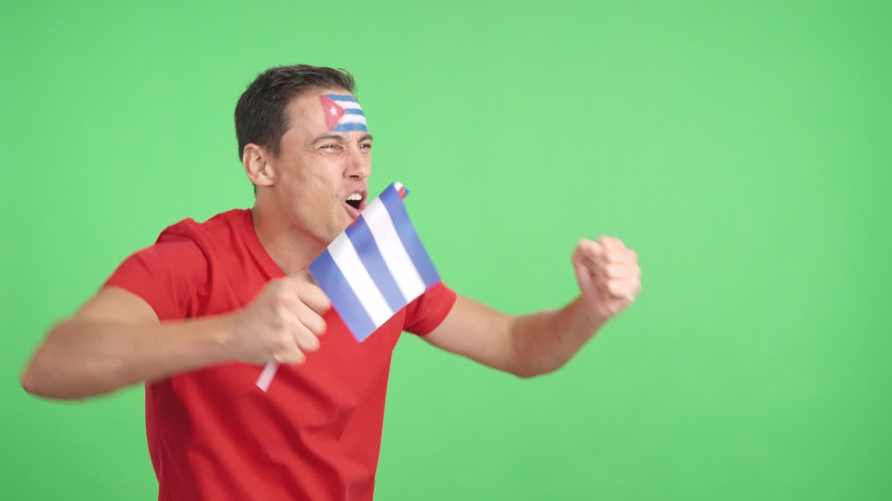Man cheering for Cuba waving a national flag looking away