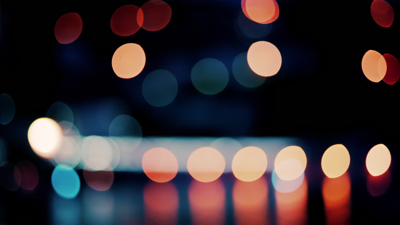 Blurry, circular light patterns in various warm and cool tones, set against a dark background