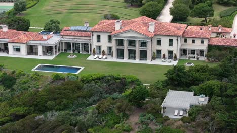 vista aérea dando vueltas por encima de la lujosa mansión de malibu y la piscina en acantilados empinados con vistas al océano pacífico