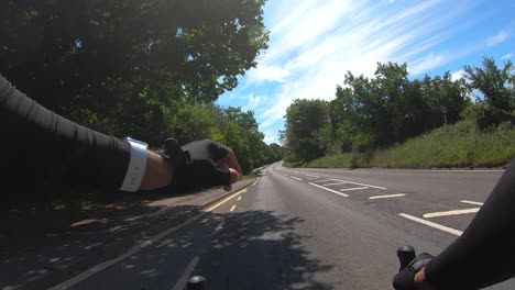 Pov-Ciclismo-En-Carretera-Vacía-Bordeada-De-árboles-Comprobando-El-Tiempo-En-La-Muñeca