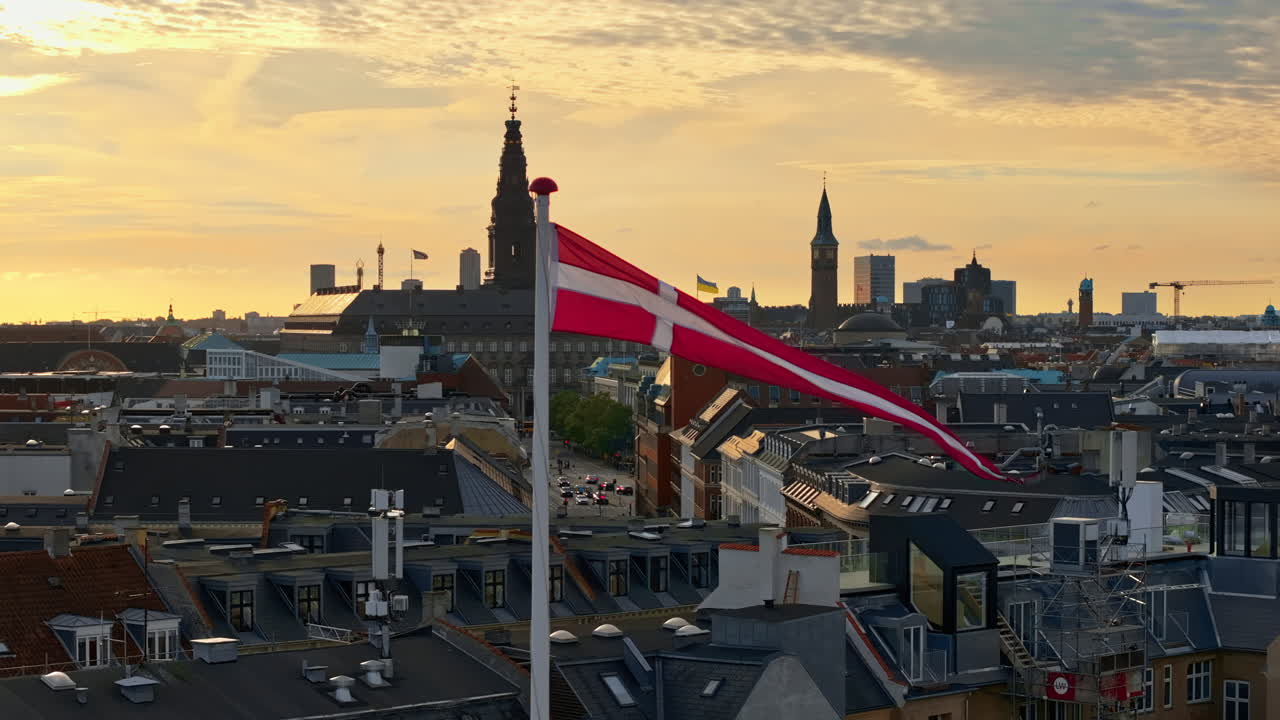 Luftfoto med drone af det danske flag, der viftes på toppen af en bygning i København ved solnedgang
