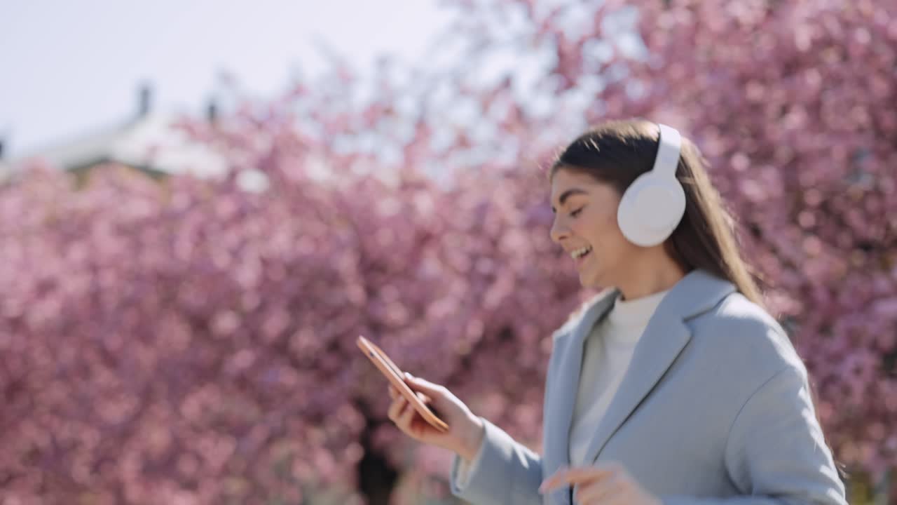 Woman listening to music in a park with cherry blossoms