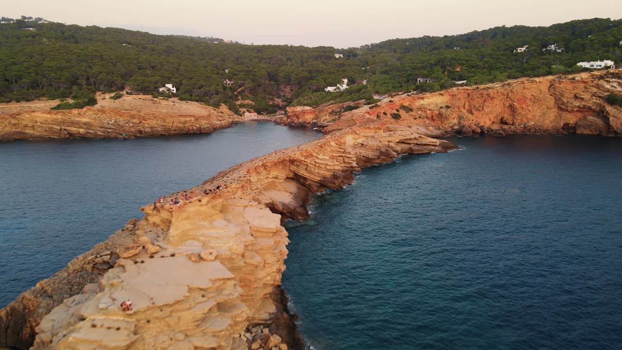 Ripresa aerea che sorvola la costa rocciosa di Punta Galera a Ibiza, verso una piccola baia insenata