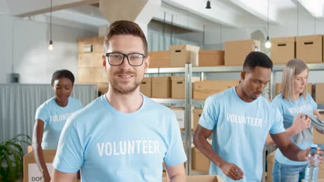 voluntario varón caucásico escribiendo en una tableta y sonriendo a la cámara