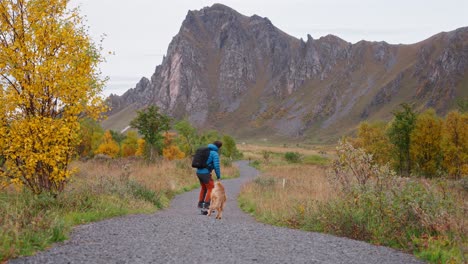A man rides a one-wheel board with a dog on a scenic trail in Vestarelen outdoors