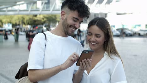 front view of smiling young couple looking at smartphone