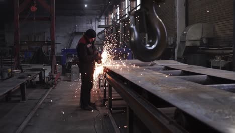 trabajador metalúrgico moliendo placas metálicas en una fábrica