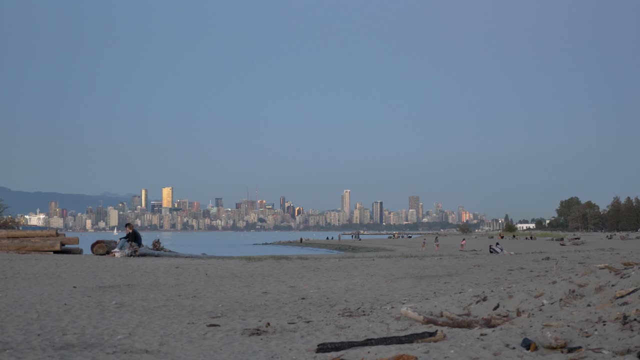 Persone sulla spiaggia sabbiosa di Spanish Banks con vista su English Bay e il centro di Vancouver, nella Columbia Britannica, Canada