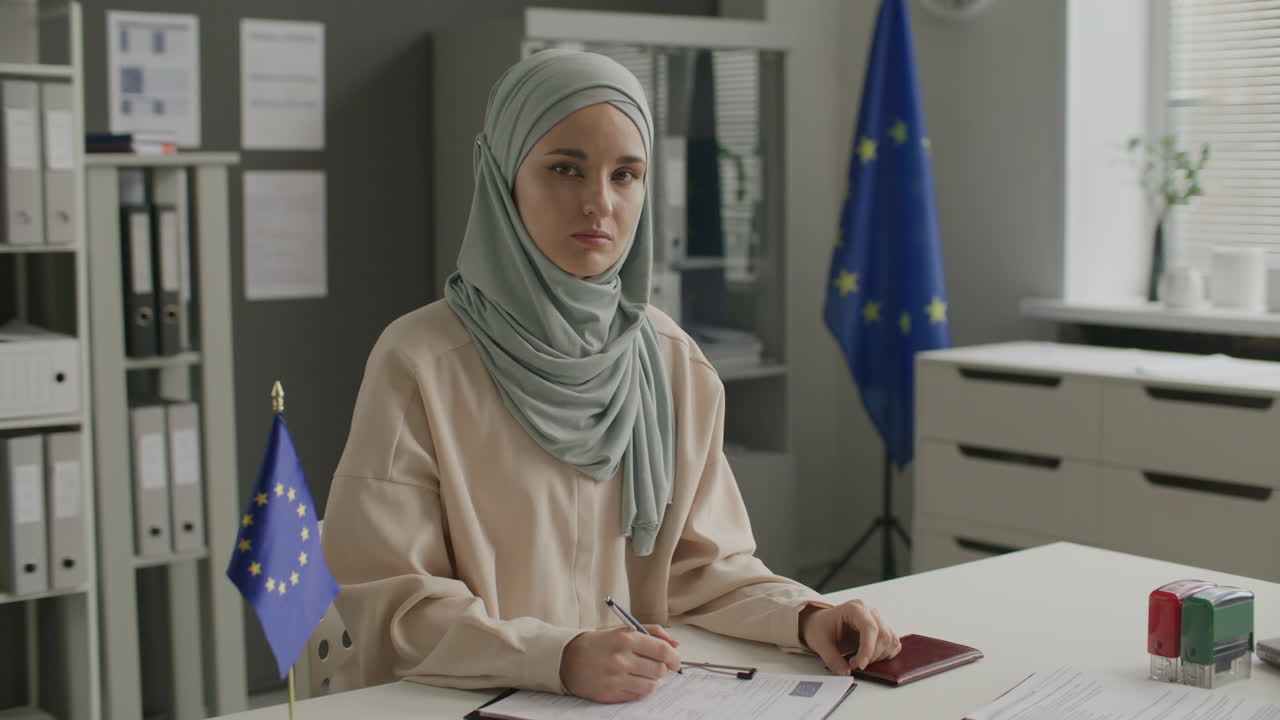 Portrét mladé muslimky vyplňující formulář žádosti na ambasádě EU