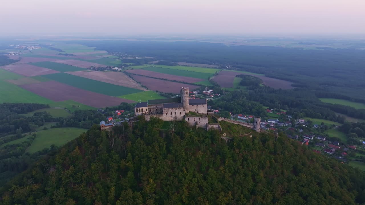 Flyfoto av Bezdez slott i solnedgang over bølgende landskap