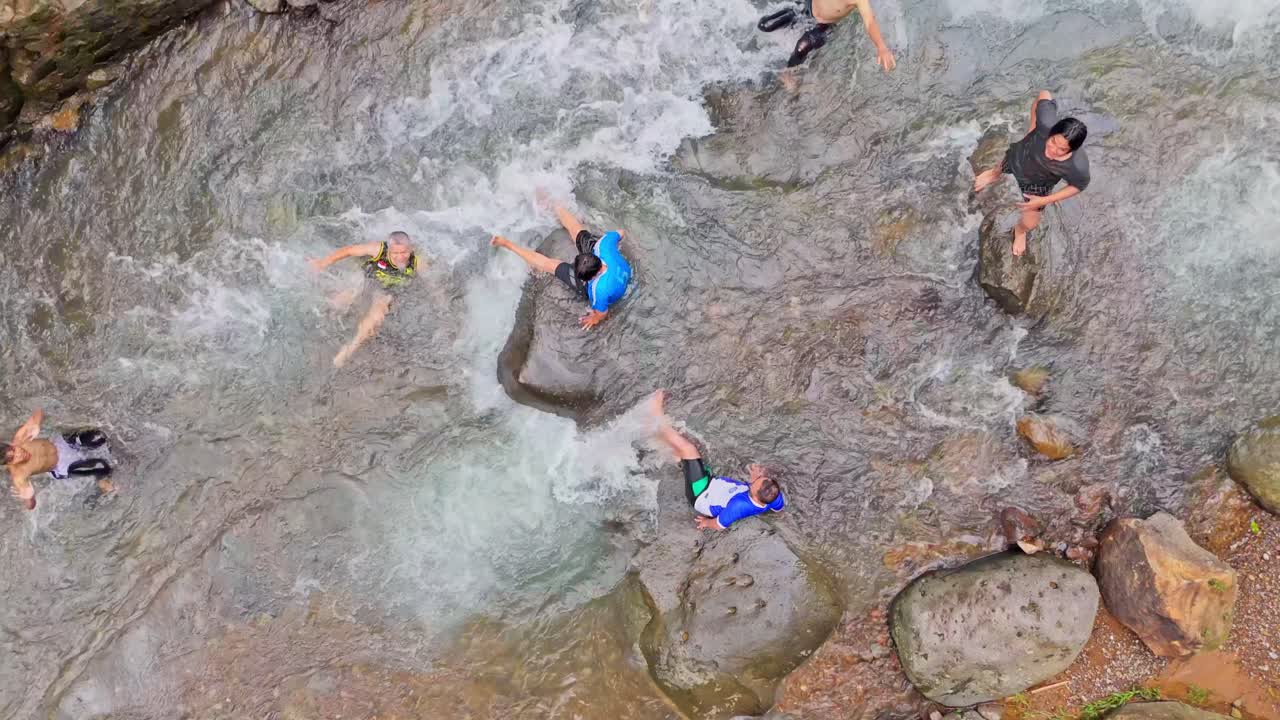 Turisti che si divertono in un fiume scenografico con massi e acqua cristallina.
