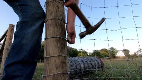 person fixing fence and putting field wire mesh in a farm near flat rock, michigan - medium shot